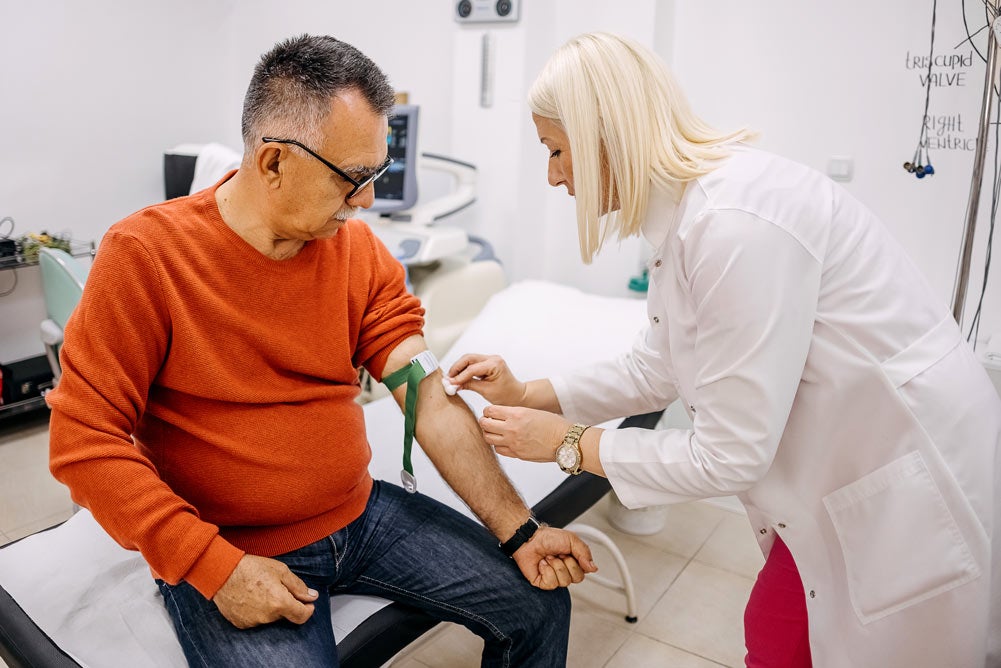 Mature man getting blood drawn by nurse